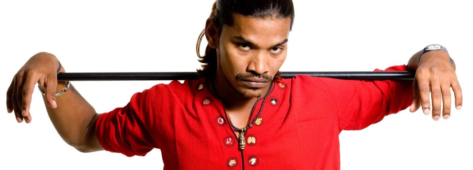 RJ Gopi of Radio City Chennai in a red kurta on a white background, a black pole balanced across both shoulders